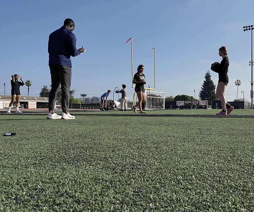 Coach directing a group of athletes through field training
