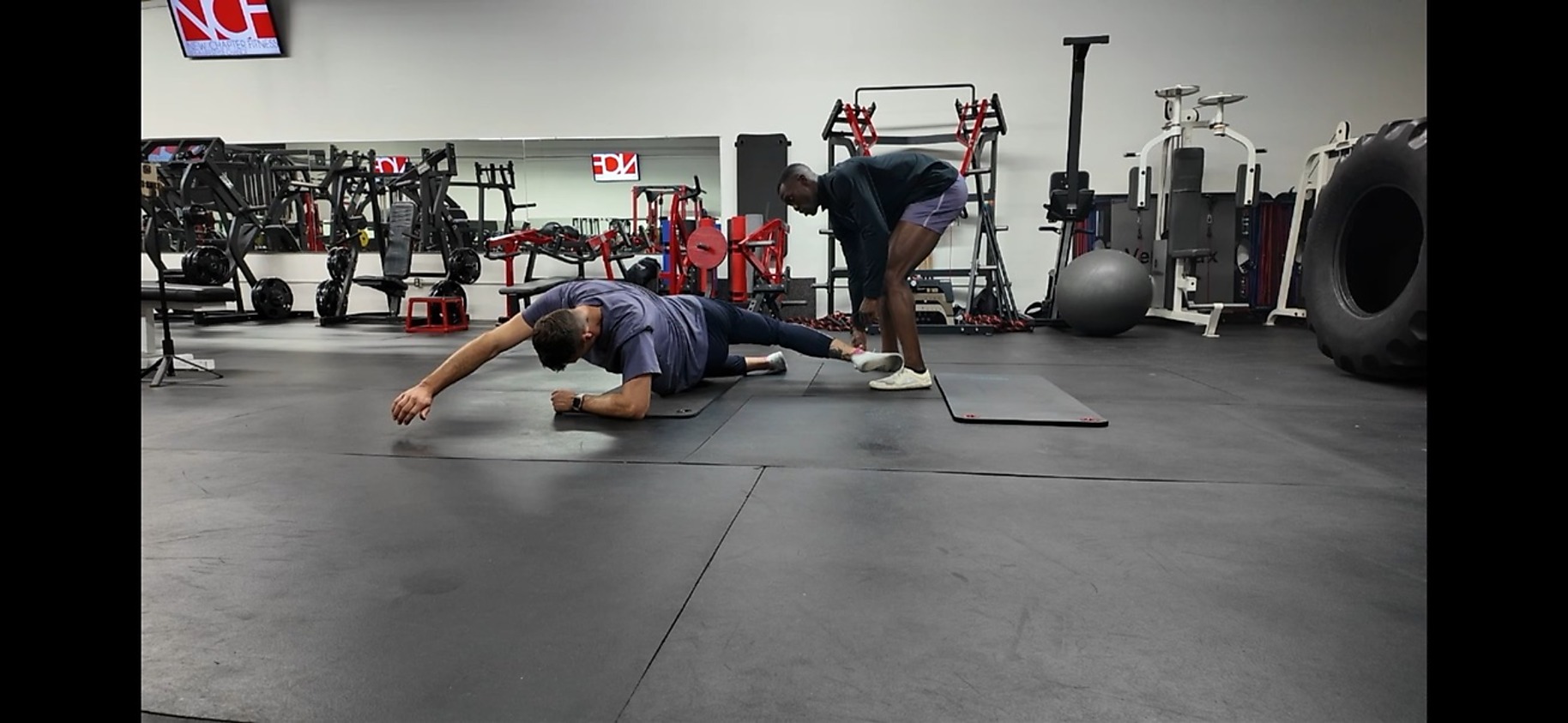 Coach spotting an athlete through a single-leg clamshell drill