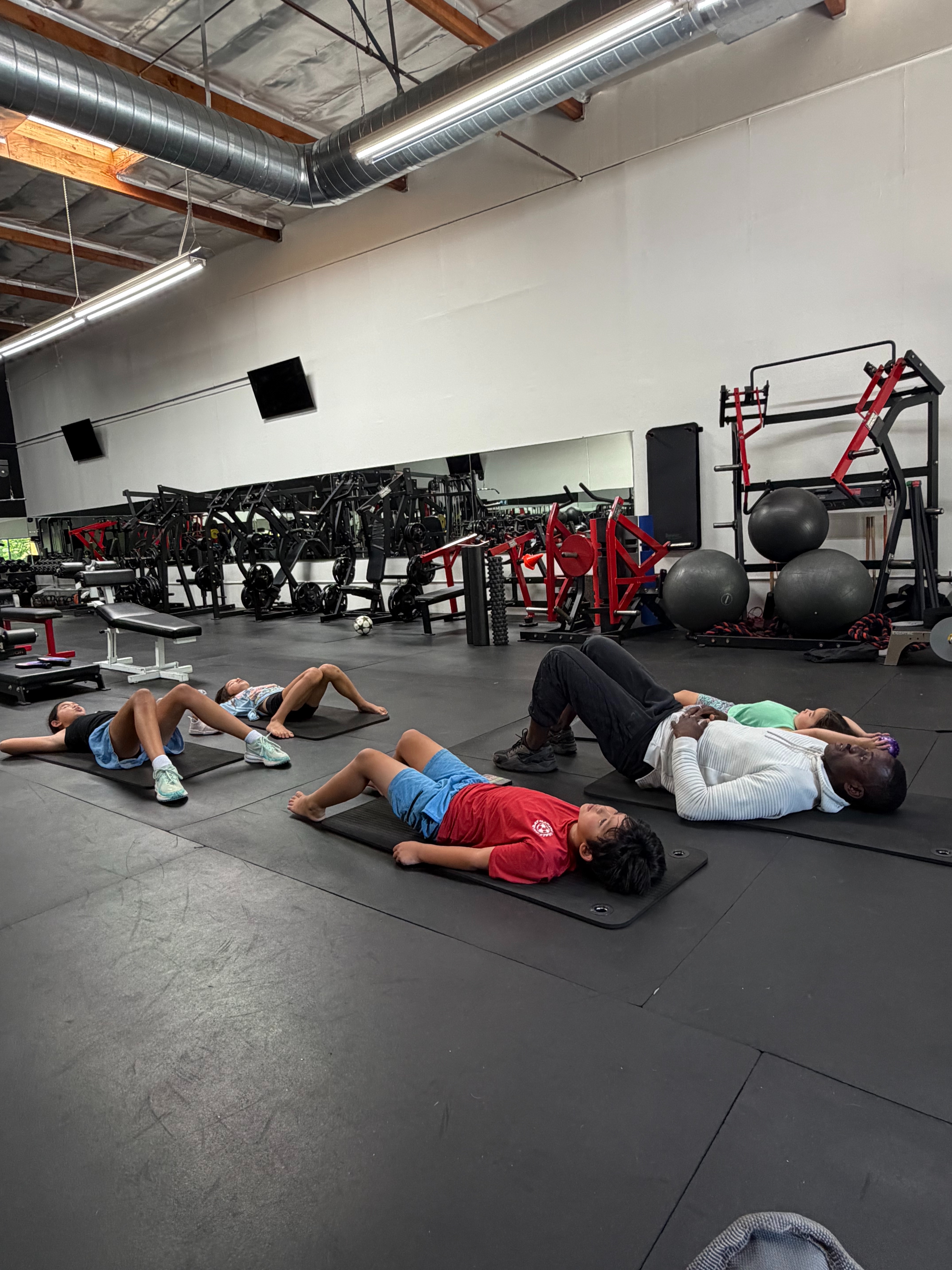 Oseoba teaching breathwork to young athletes on gym mats